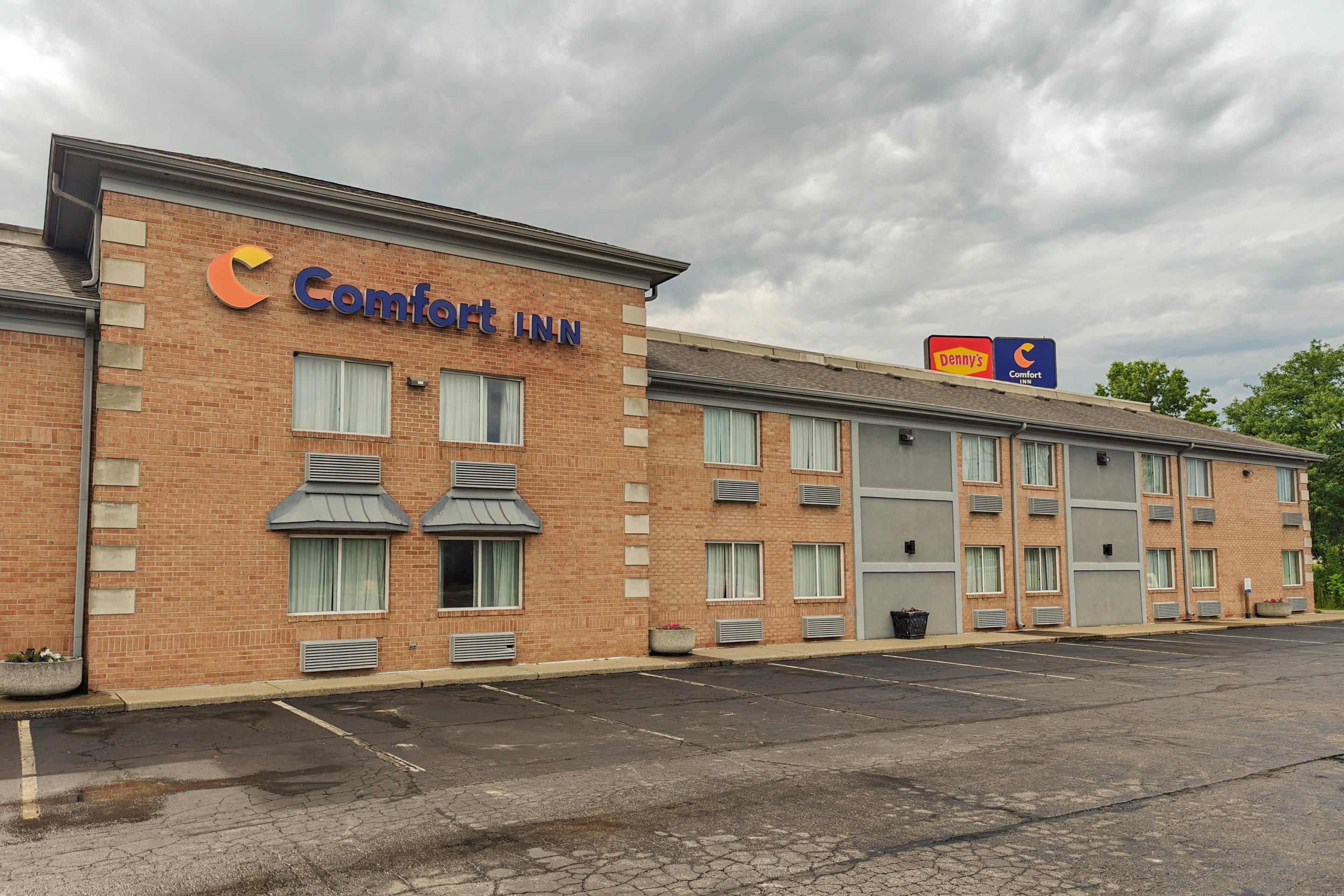 A brick building with a sign for Comfort Inn. There are multiple windows and air conditioning units.