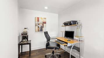 Un pequeño espacio de oficina con un escritorio, una silla, computadora, impresora y máquina de café.