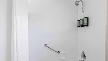A white bathroom with a shower, a towel rack, and a soap dispenser.