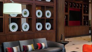 A modern living room with a dark sofa, a black coffee table, and a large wooden shelving unit displaying decorative plates.