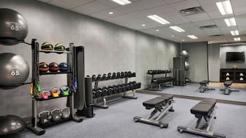 A gym with exercise equipment, including dumbbells, kettlebells, and a bench.