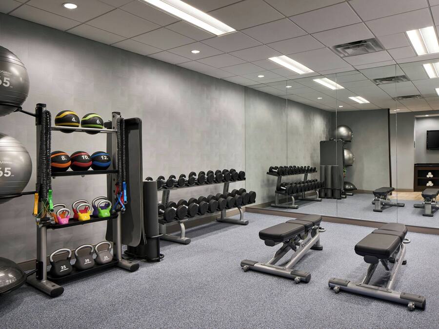 A gym with exercise equipment, including dumbbells, kettlebells, and a bench.