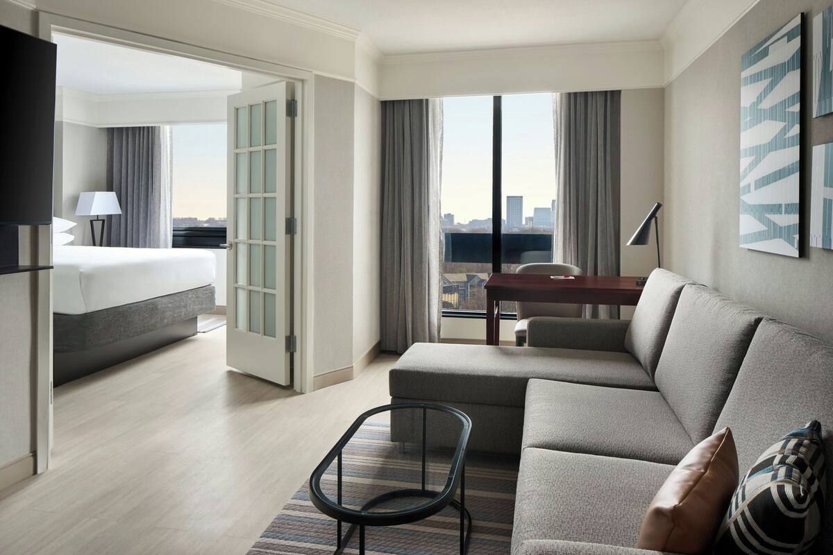 A hotel room with a bed, a sofa, a small table, and a TV.