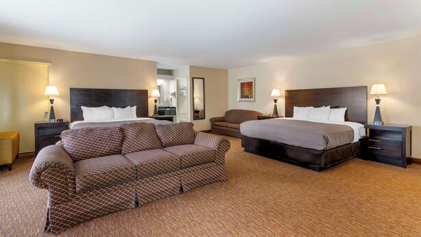 Une chambre d’hôtel avec deux lits, un canapé et un petit fauteuil.