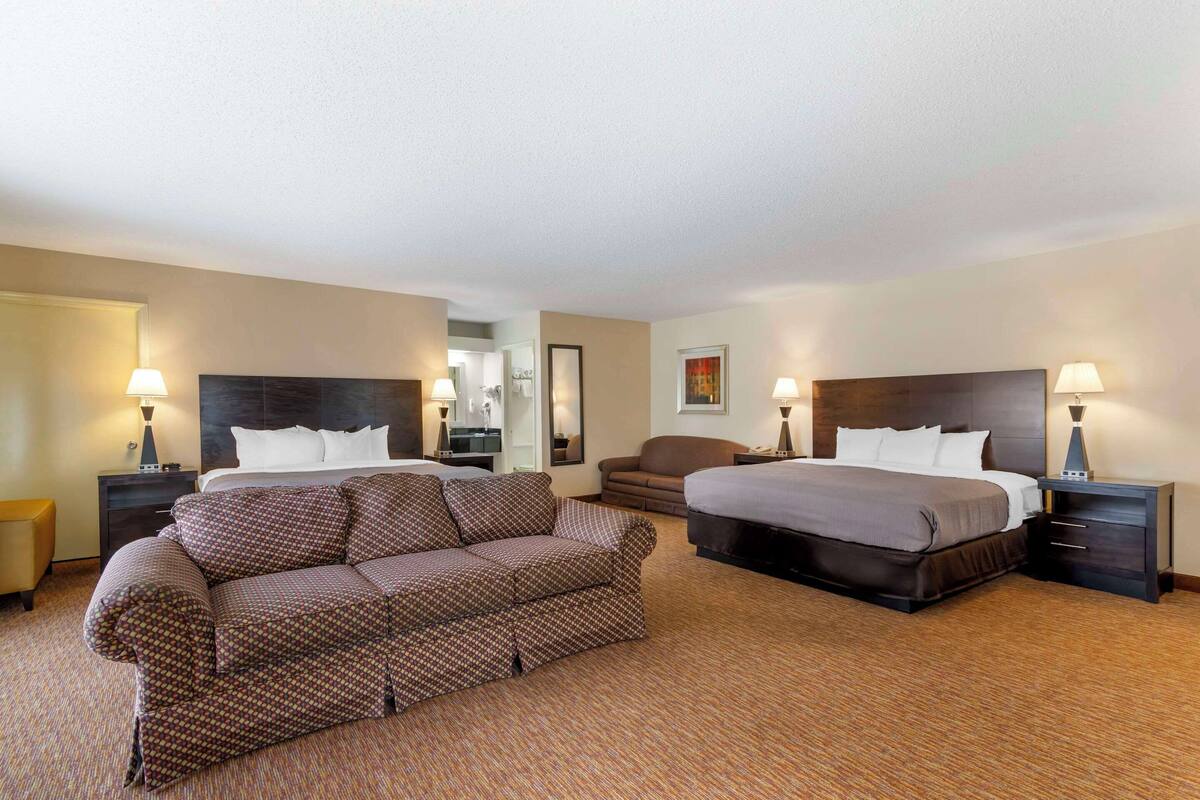 A hotel room with two beds, a sofa, and a small armchair.