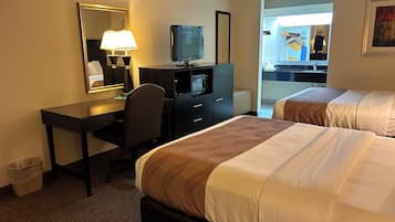 A hotel room with a desk, two beds, a television, and a mirror.