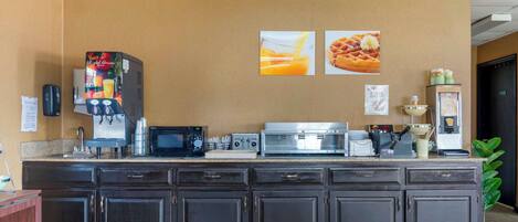 A kitchen area with a coffee machine, microwave, toaster, and refrigerator.