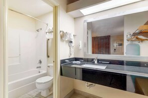 A modern bathroom with a bathtub, toilet, and vanity with a mirror.
