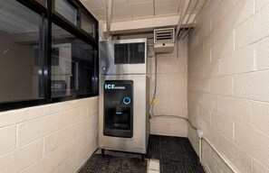 Un dispensador de hielo en una esquina con una ventana y un muro de ladrillo.