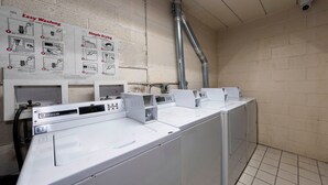 A laundry facility with multiple washing machines and a wall-mounted instruction sign. - Red Roof Inn Bordentown - McGuire AFB (Bordentown)