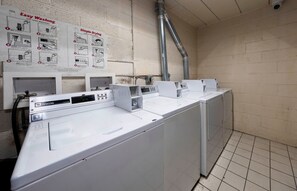 A laundry facility with multiple washing machines and a wall-mounted instruction sign. - Red Roof Inn Bordentown - McGuire AFB (Bordentown)
