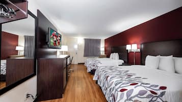 A hotel room with a large bed, a desk, a television, and a mirror.