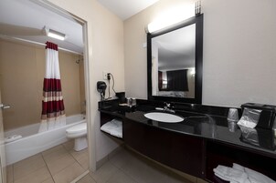 A modern bathroom with a bathtub, toilet, and a large mirror above the sink.