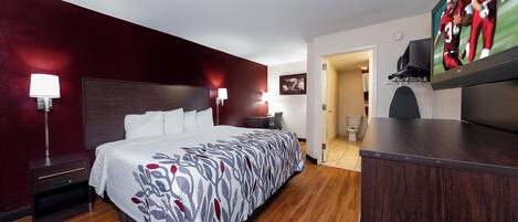 Habitación de hotel con una cama grande, un escritorio, un televisor y una puerta que da a un baño.
