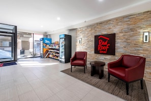 Un vestíbulo de hotel con un letrero de Red Roof, una máquina expendedora de helado Blue Bunny y sillones de cuero.
