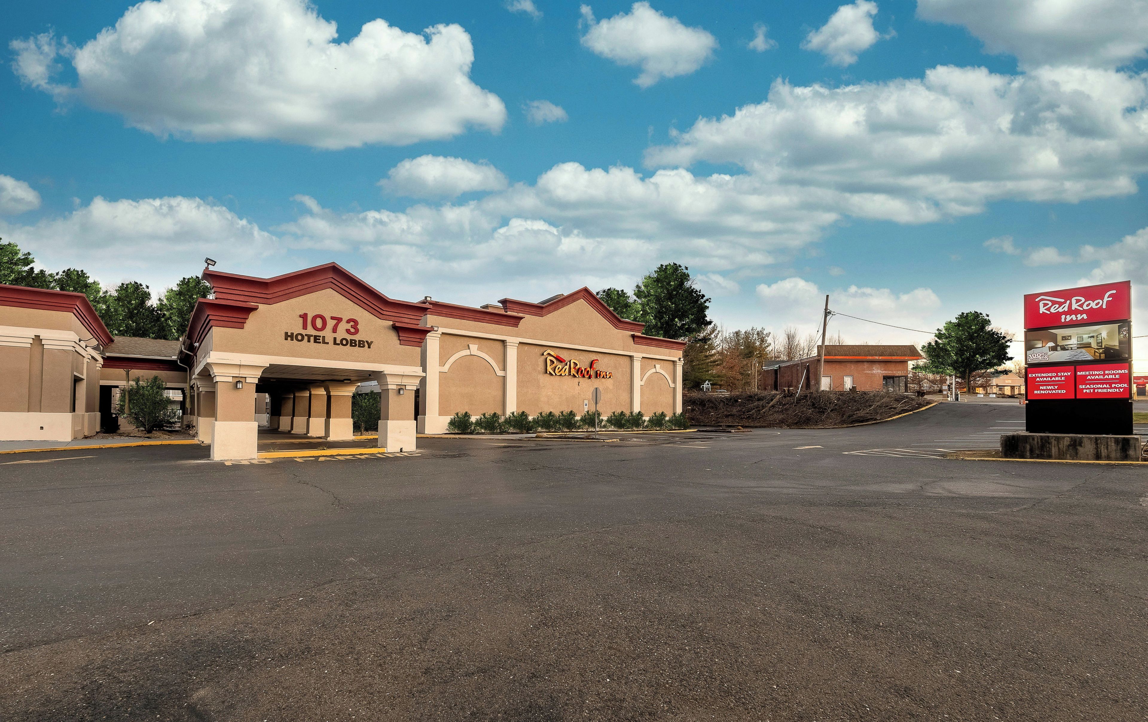 A Red Roof Inn with a 1073 Hotel Lobby, a parking lot, and a clear sky.