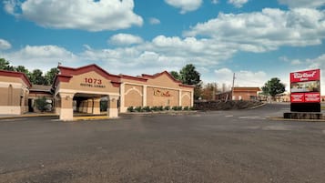 A Red Roof Inn with a 1073 Hotel Lobby, a parking lot, and a clear sky.