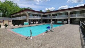 Un hotel con piscina, varios balcones y un pequeño edificio con garaje.