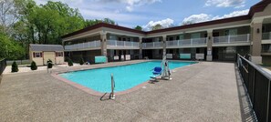 Un hotel con piscina, varios balcones y un pequeño edificio con garaje.