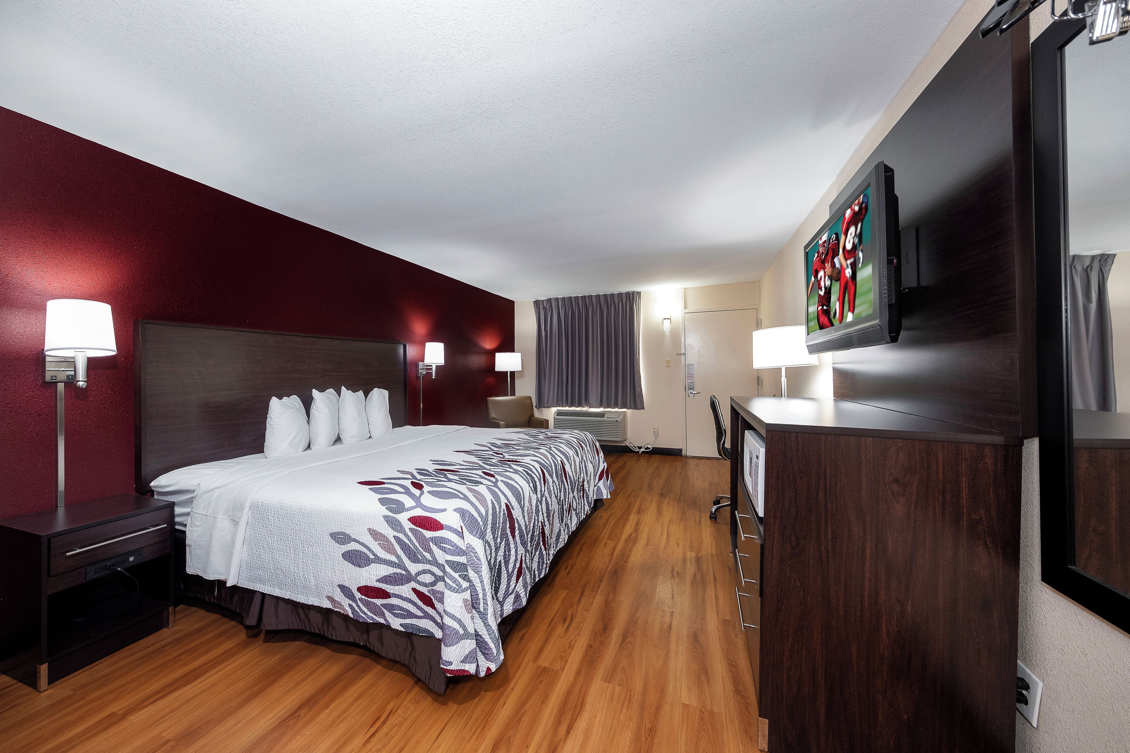 Ein Hotelzimmer mit einem großen Bett, Nachttischlampen, einem Flachbildfernseher und einem Schreibtisch mit Stuhl.