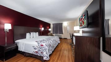 Ein Hotelzimmer mit einem großen Bett, Nachttischlampen, einem Flachbildfernseher und einem Schreibtisch mit Stuhl.