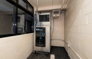 Un dispensador de hielo en una esquina con una ventana y un muro de ladrillo.