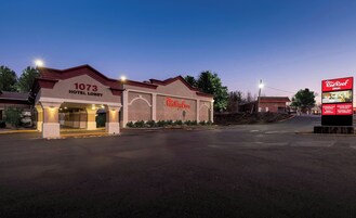 A Red Roof Inn hotel lobby with a number 1073 sign, a large Red Roof Inn sign, and a billboard advertising extended stay and meeting rooms.