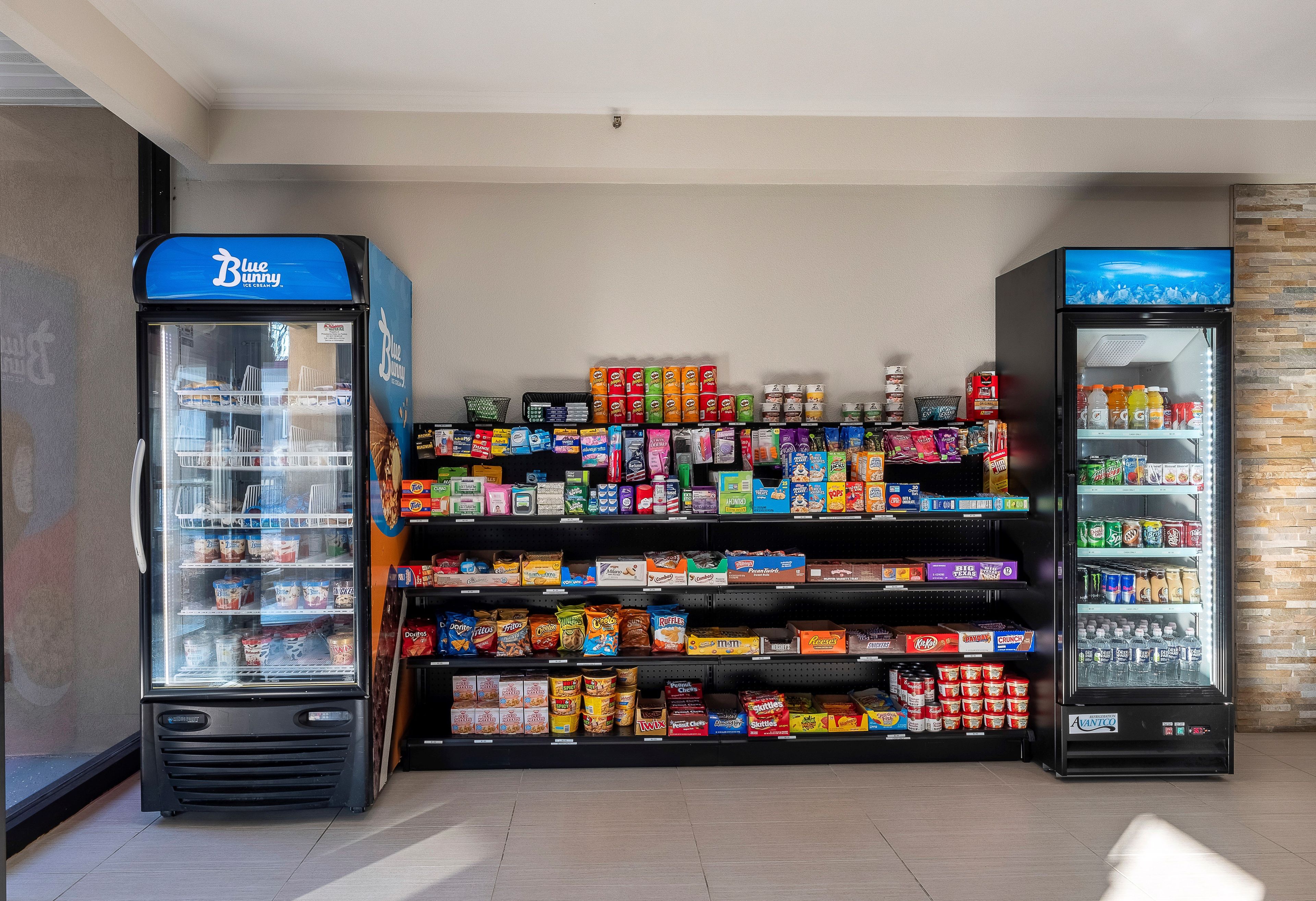 A vending machine area with a Blue Bunny ice cream machine and a refrigerated display case with various snacks and beverages.