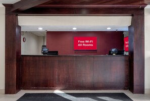 Un comptoir d’accueil avec un panneau rouge indiquant que le Wi-Fi est disponible gratuitement dans toutes les chambres.