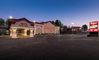 A Red Roof Inn hotel lobby with a number 1073 sign, a large Red Roof Inn sign, and a billboard advertising extended stay and meeting rooms.