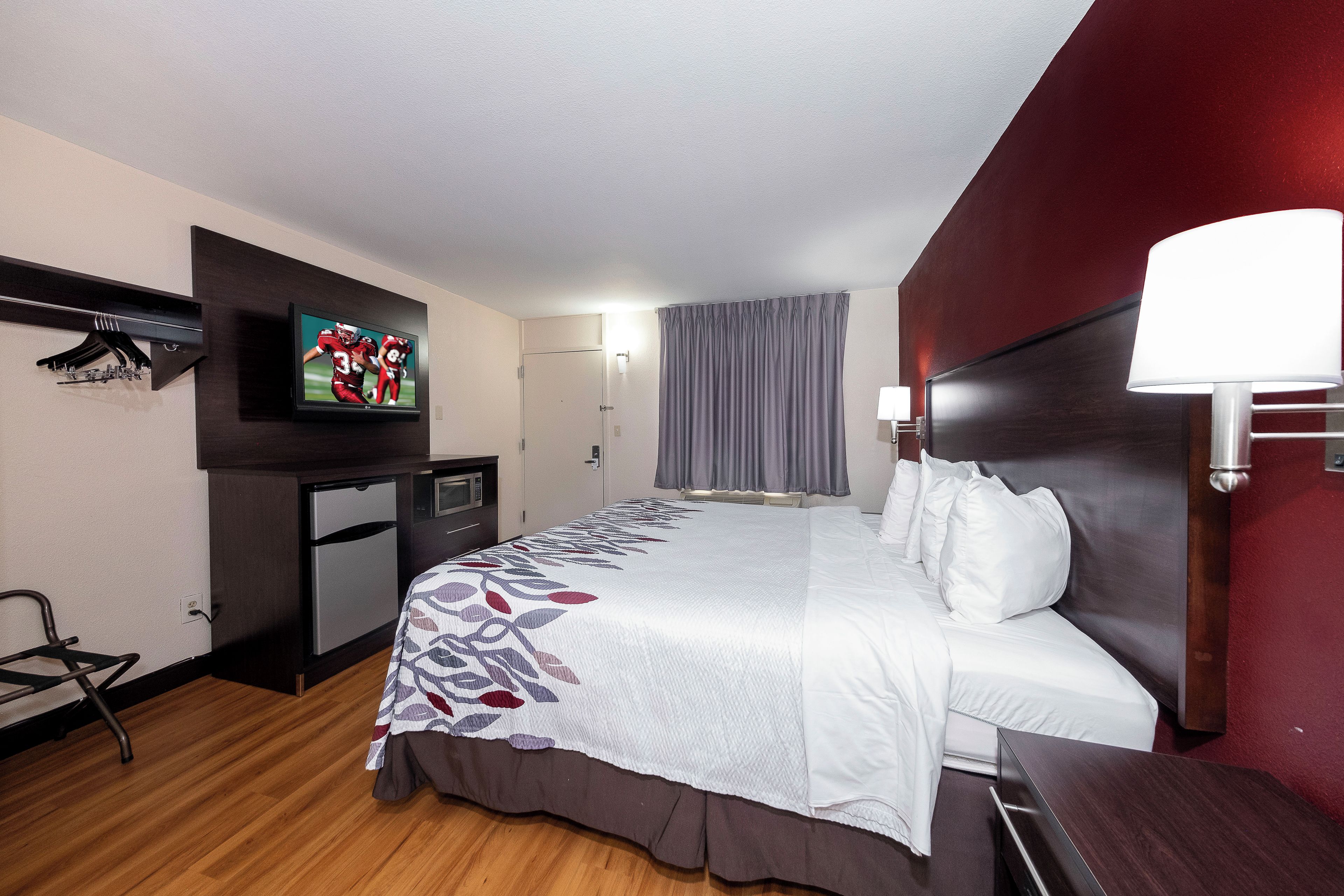 Habitación de hotel con una cama, televisor montado en la pared, escritorio y una silla.