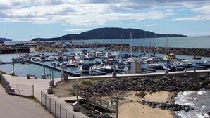 A marina with numerous boats docked, a rocky shoreline, and a distant island. - Comfort Inn Sept-Iles - Cotes Nord (Sept-Iles)