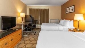 A hotel room with two beds, a desk with a TV, and a chair.
