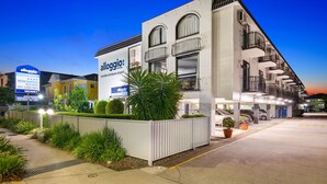 Un hôtel avec une enseigne indiquant que les chambres ont été rénovées, un parking et une façade bien éclair ée.