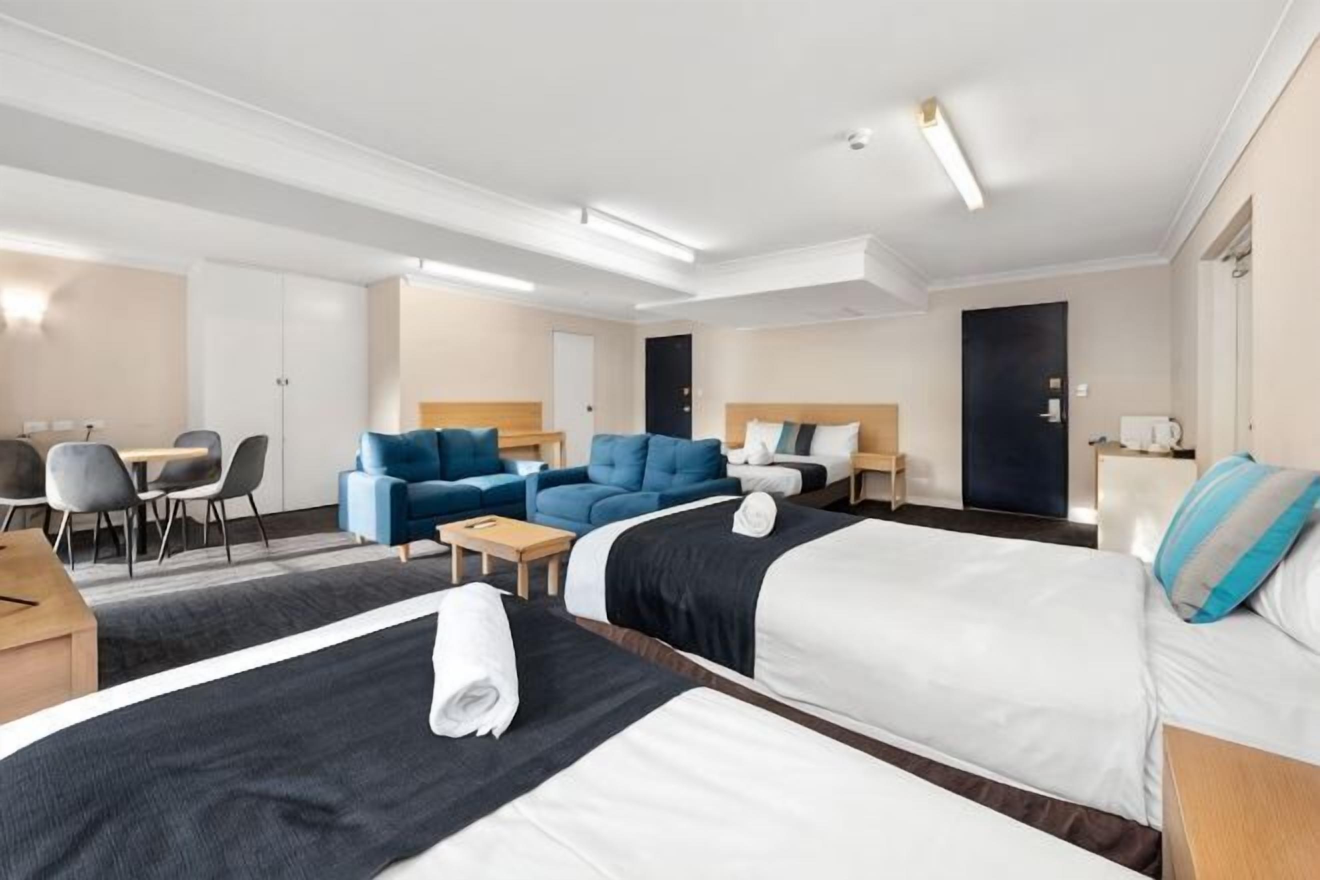 A hotel room with two beds, a sofa, a desk, and a chair.