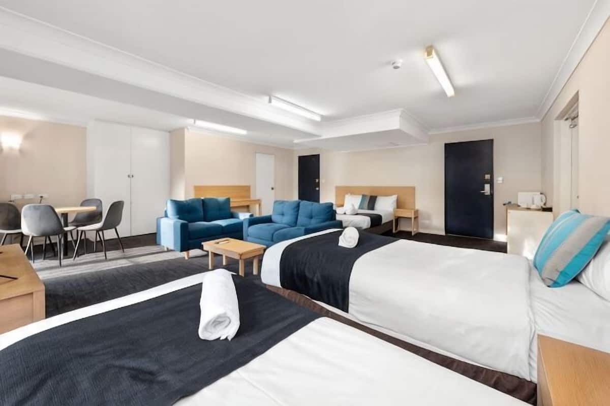 Una camera d'albergo con due letti, un divano, una scrivania e una sedia.