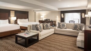 A hotel room with a large bed, two sofas, a coffee table, and a TV.
