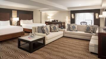 Habitación de hotel con una cama grande, dos sofás, una mesa de centro y un televisor.