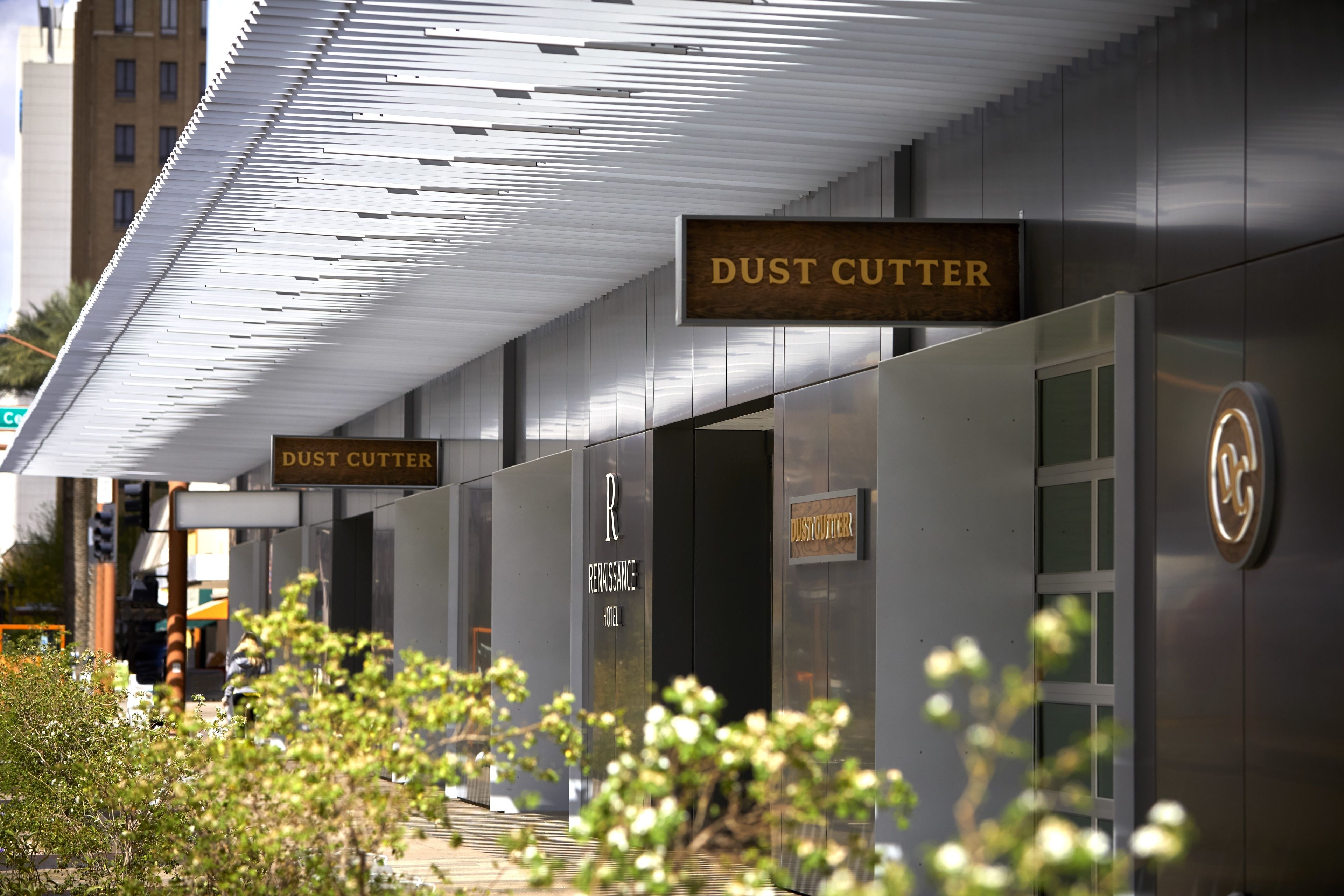 L’extérieur d’un hôtel moderne, avec une enseigne indiquant « DUST CUTTER » et une autre indiquant « RENAISSANCE HOTEL ».
