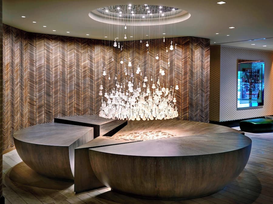 A modern lobby with a circular reception desk, a hanging light fixture, and a patterned wall.