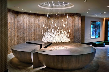 A bar area with a long counter, multiple stools, and a variety of bottles. at Renaissance Phoenix Downtown Hotel