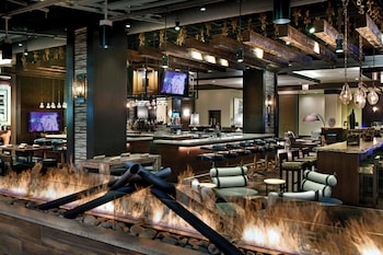 A modern cafe with large windows, wooden tables, and hanging pendant lights. at Renaissance Phoenix Downtown Hotel