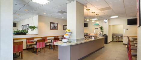 A hotel lobby with a reception desk, seating area, and a clock on the wall.