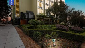 A hotel courtyard with a well-maintained garden, a barbecue grill, and a Comfort Inn sign. - Comfort Inn by the Bay (San Francisco)