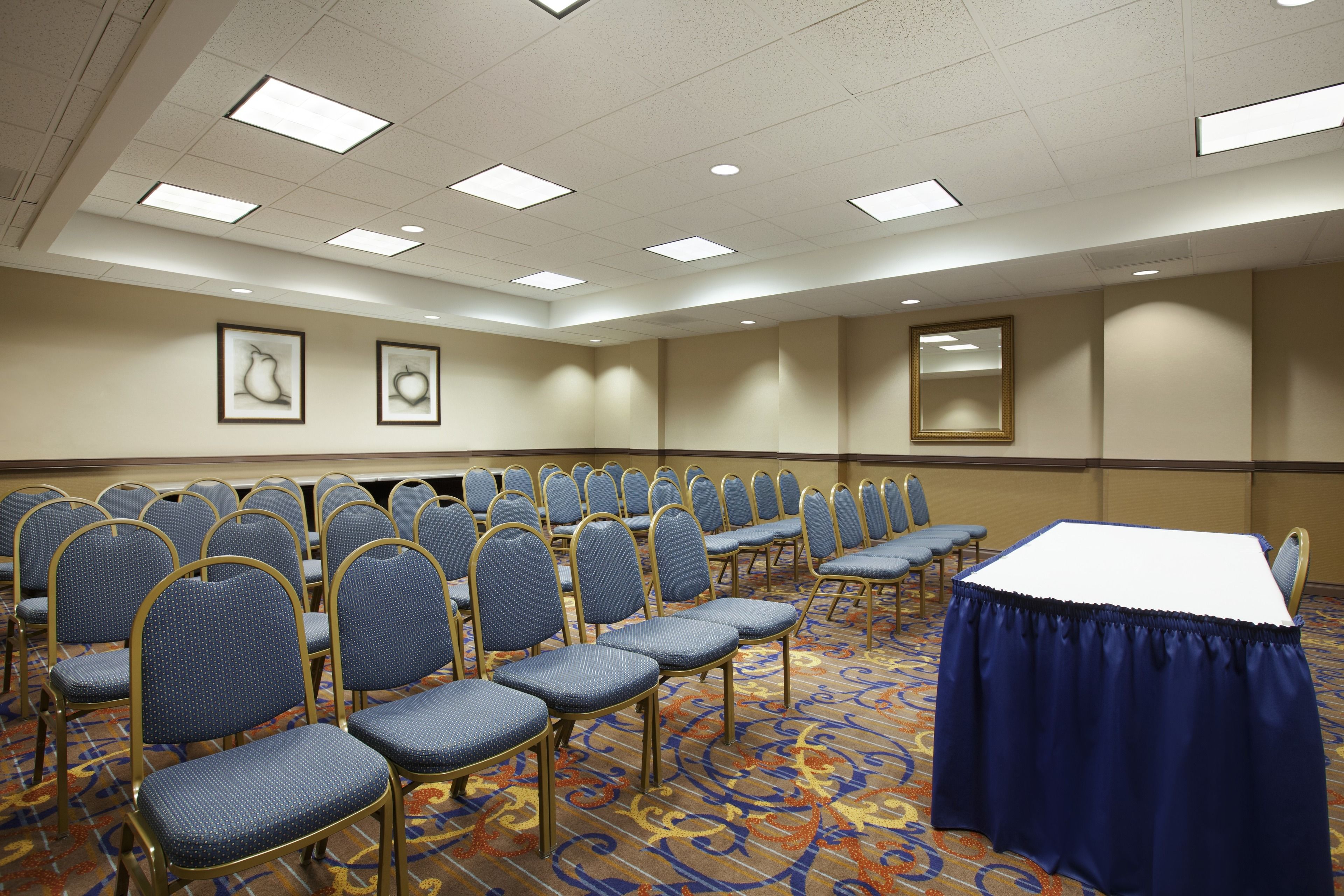 A conference room with rows of chairs, a table, and framed artwork on the walls.