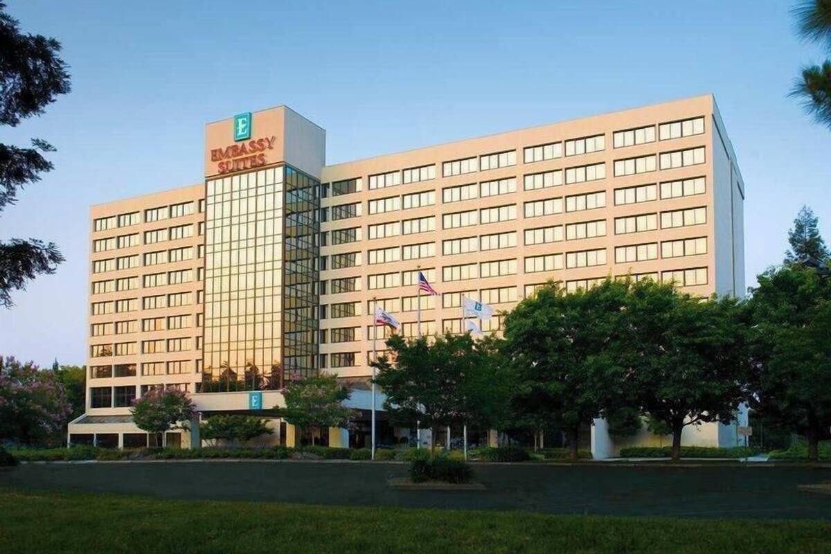 A large hotel building with multiple floors, a prominent 'Embrassy Suites' sign, and several flags.