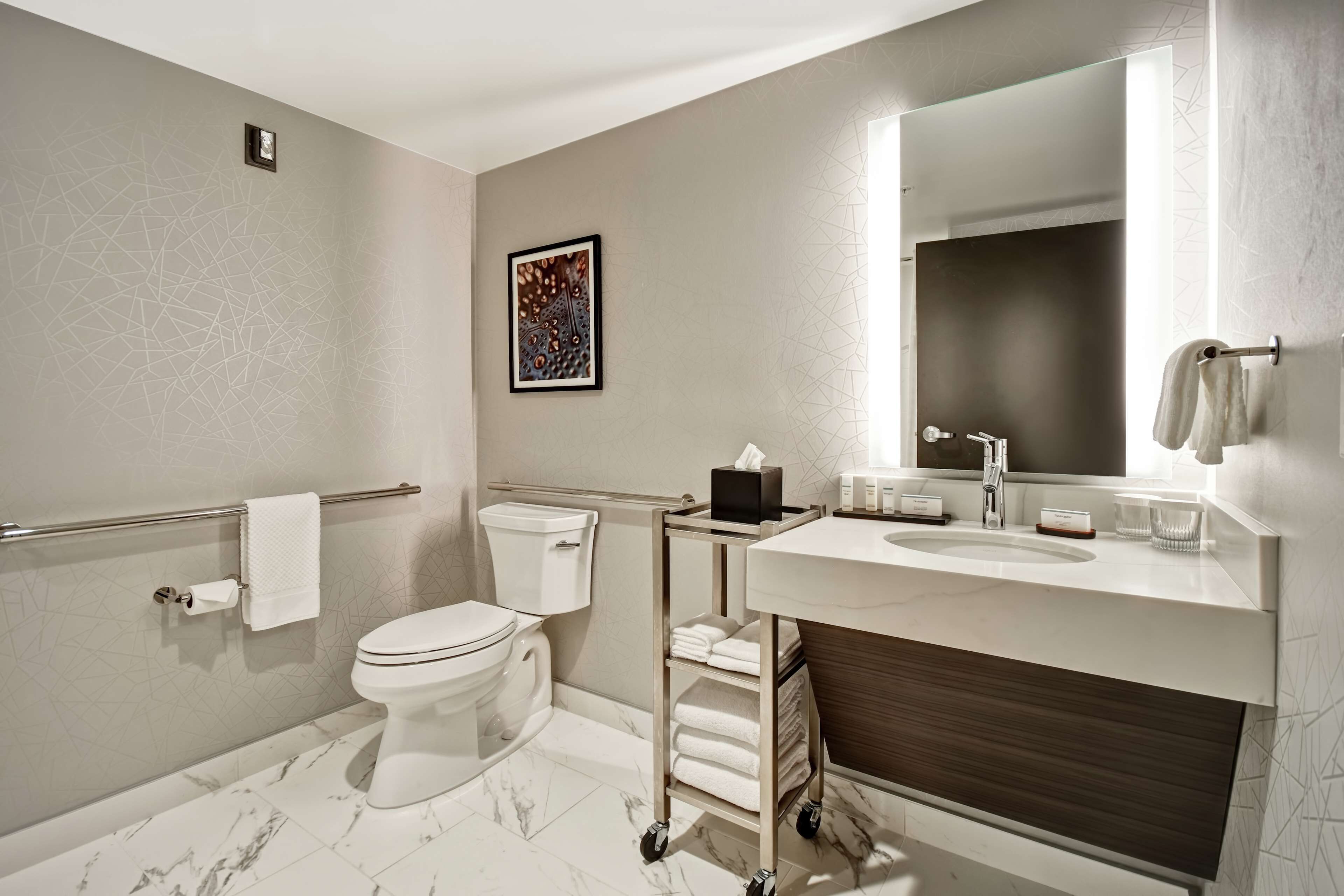 A modern bathroom with a toilet, sink, and a large mirror.