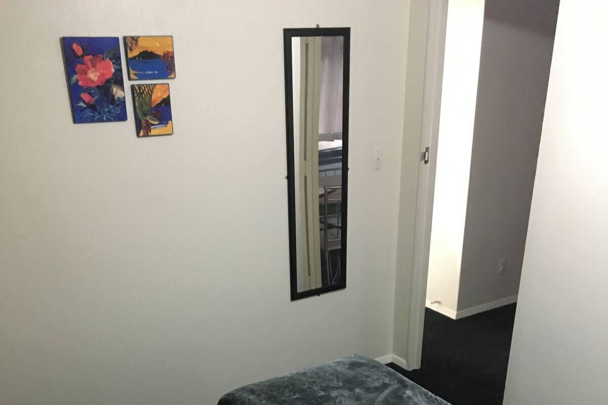 Un dormitorio con una cama, un almohadón rojo y dos cuadros en la pared.