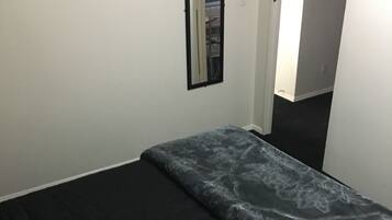 Ett sovrum med en säng, en röd kudde och två tavlor på väggen.