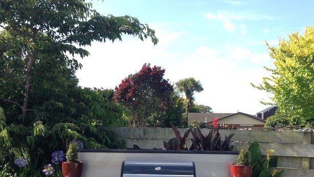 An outdoor barbecue grill with a table in a garden setting.